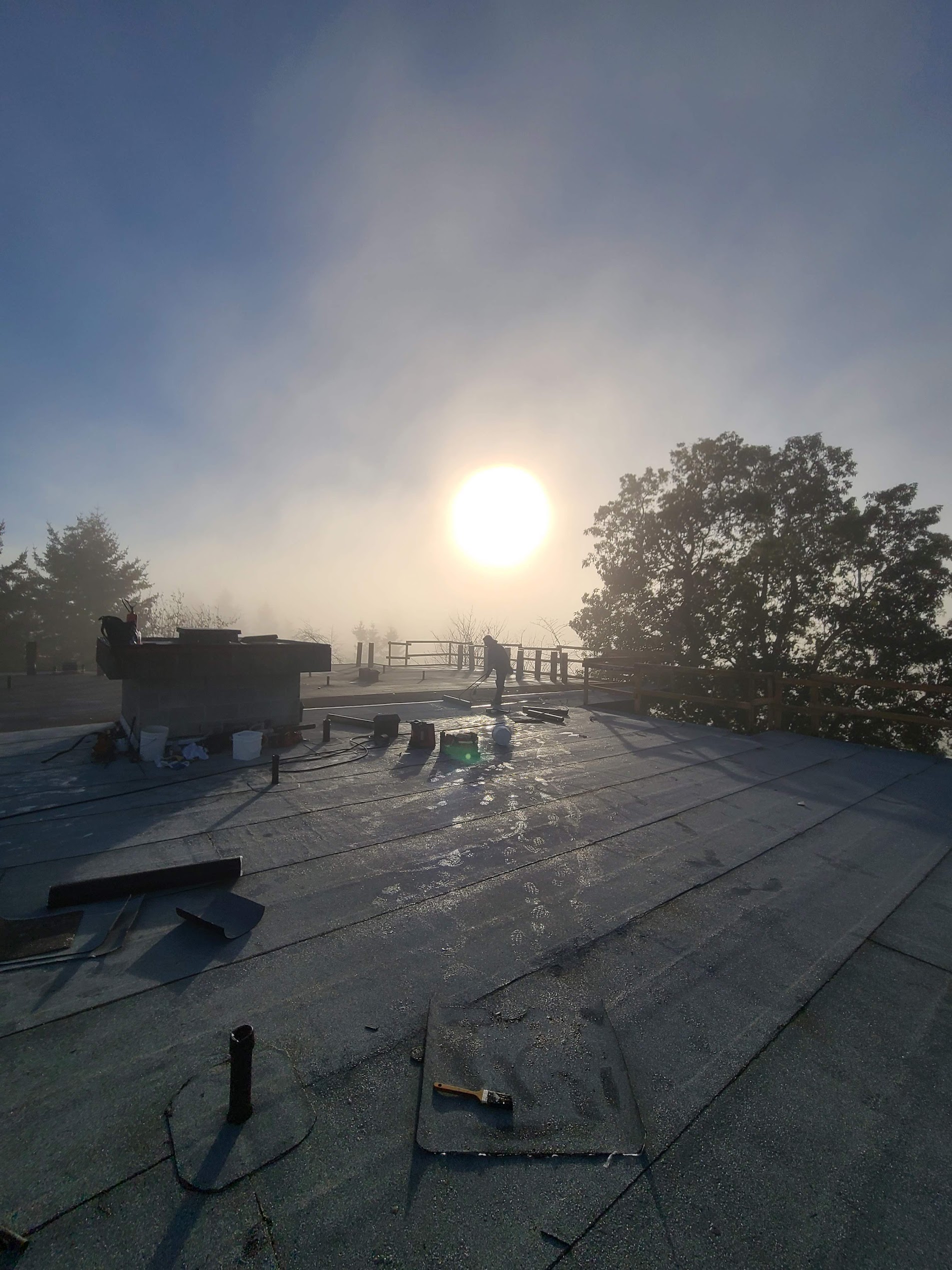 Torch-on flat roofing work at sunrise